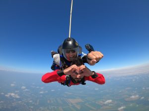 Un instructeur tandem sourit alors que son passager fait une forme de coeur avec ses mains. 