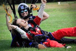 Une femme remplie de joie lève les bras au ciel alors qu'elle touche le sol après son saut en parachute.