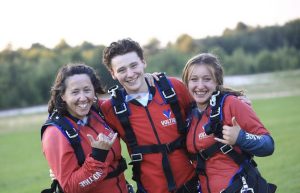 Une mère, son garçon et sa fille souriants posent pour la caméra après avoir vécu un saut en parachute en famille chez Voltige.